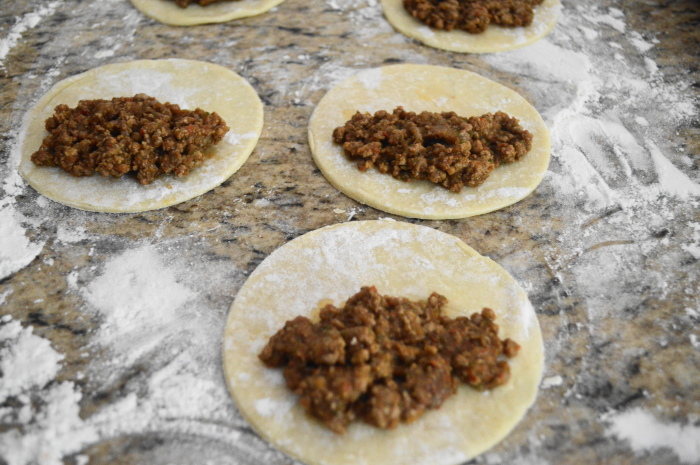 The beef empanadas cut out and filled, ready to be sealed. 