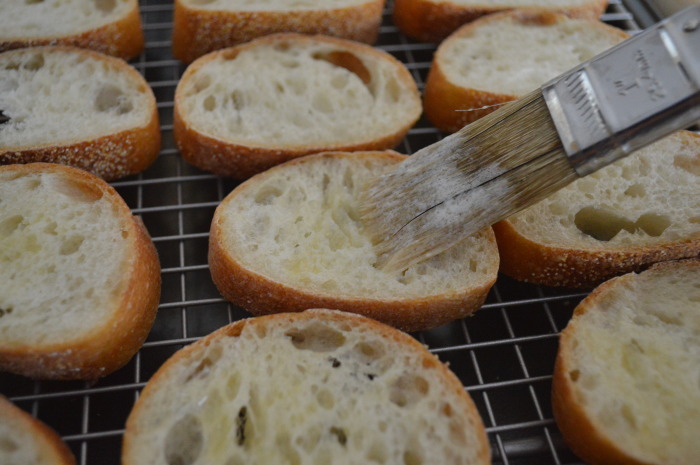 Brushing the little crostini with butter.
