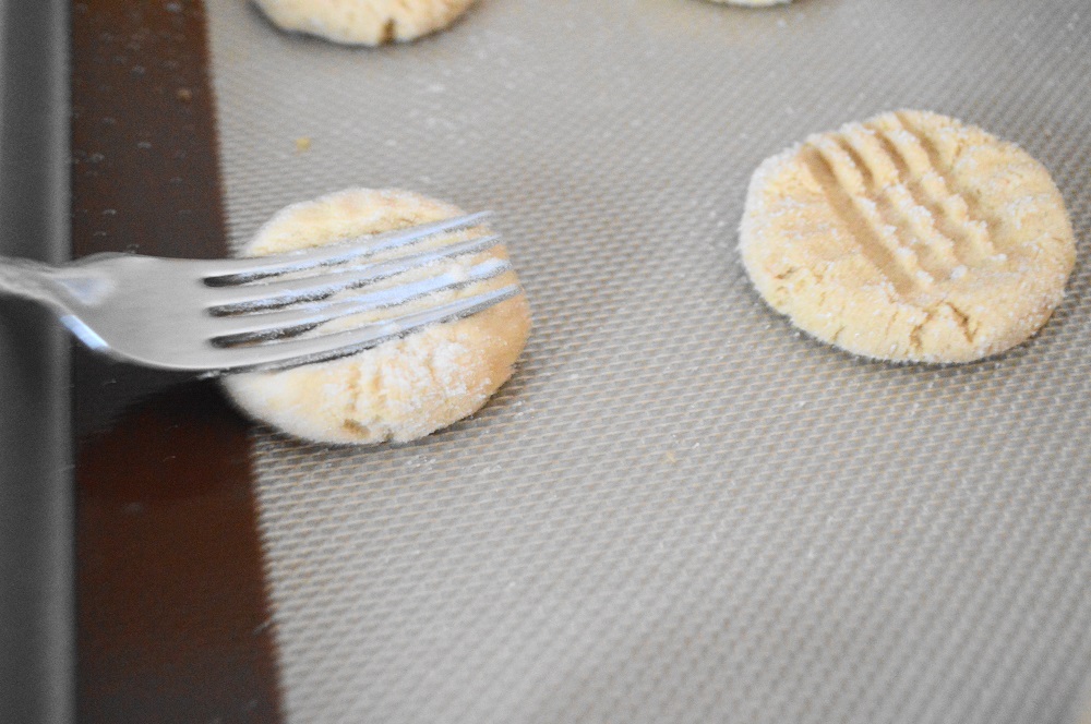 I used my cookie scoop to get perfect portions of the dough. I rolled them into balls and coated them in sugar. The final touch was to use a fork to give the peanut butter cookies their signature criss cross marks. I just gently pressed down the center vertically and then horizontally.