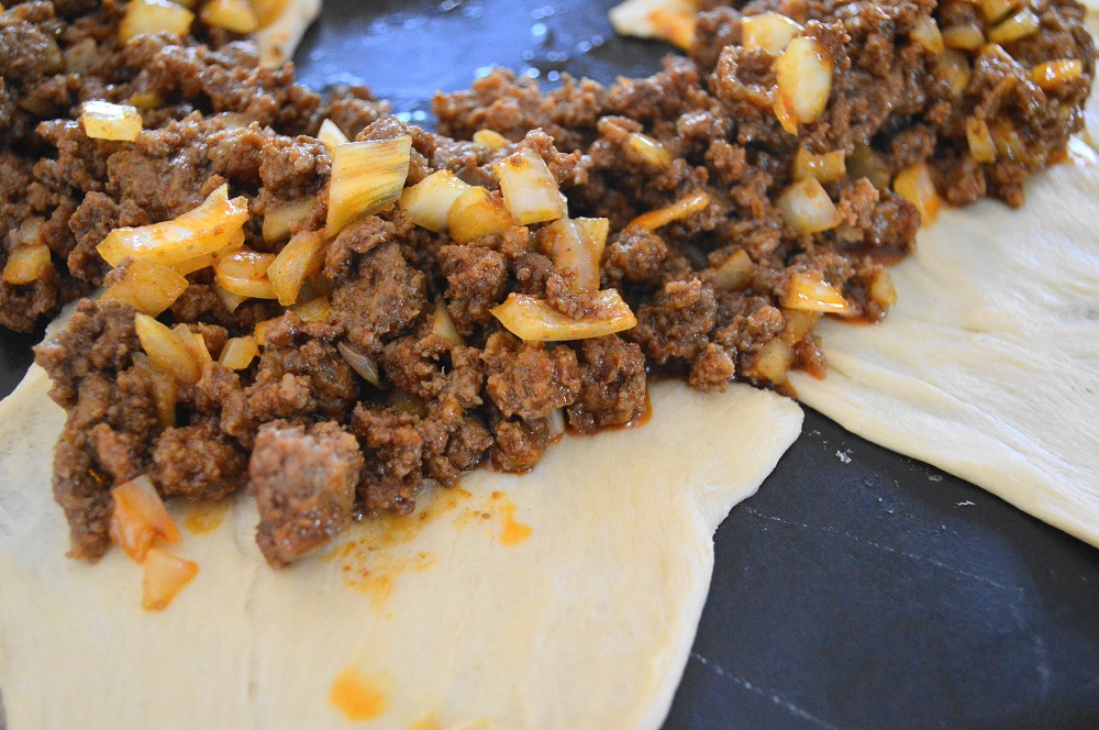 I used a round pizza stone to assemble the taco crescent ring. I was able to get the bottom a little more solid and crispy that way since the filling could make it a bit soggy. The crescent rolls came out of the can rolled up with 2 triangles stuck together in a rectangle. I laid out 8 rectangles with the short ends touching together to form the ring. Then I filled it with the beef mixture, lots of shredded cheese, chopped lettuce and salsa. To close the ring, I brought the other halves of the rectangles over the filling and pinched them into the bottom. 