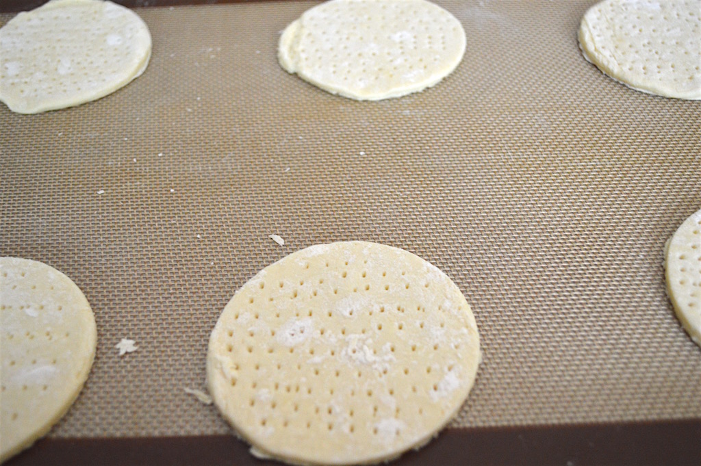 First, I used my biscuit cutter to cut out perfect little rounds from my puff pastry sheet. I was able to get 6 ready made and flaky crusts for the artichoke, tomato and goat cheese tartlets from that one sheet with virtually no effort! I pierced each of them all over in the middle, leaving a thin border. That allowed for the middle to not puff up as much as the edge to enclose the filling. 