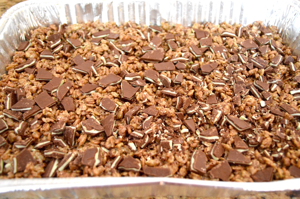 To keep the mint chocolate crispy treats from being too sweet, I made sure to add a little salt before stirring in chocolate rice cereal. I had to get the chocolate version of everyone's favorite rice cereal to go with the mint since mint chocolate is my favorite combination in the world! Then I pressed out the mixture into my well greased 9 x 13 pan. The final touch was to add a whole bunch of chopped chocolate mint candies on top while the mixture was still hot. That way they could meld right in and stay put. 