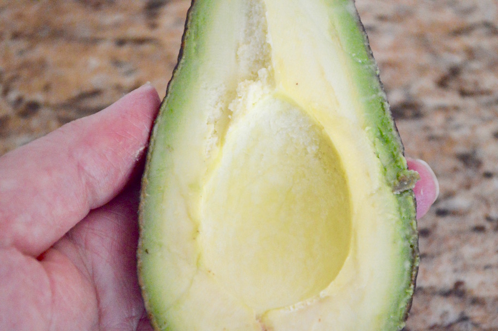 The hardest part of making the easy smokey guacamole was picking out the perfect avocados. I planned ahead and bought mine a couple of days before I needed them. That way I made sure that they would be perfectly ripe and soft when I made the guacamole. I split them in half and removed the pits first, then just scooped the flesh right into my mortar. 